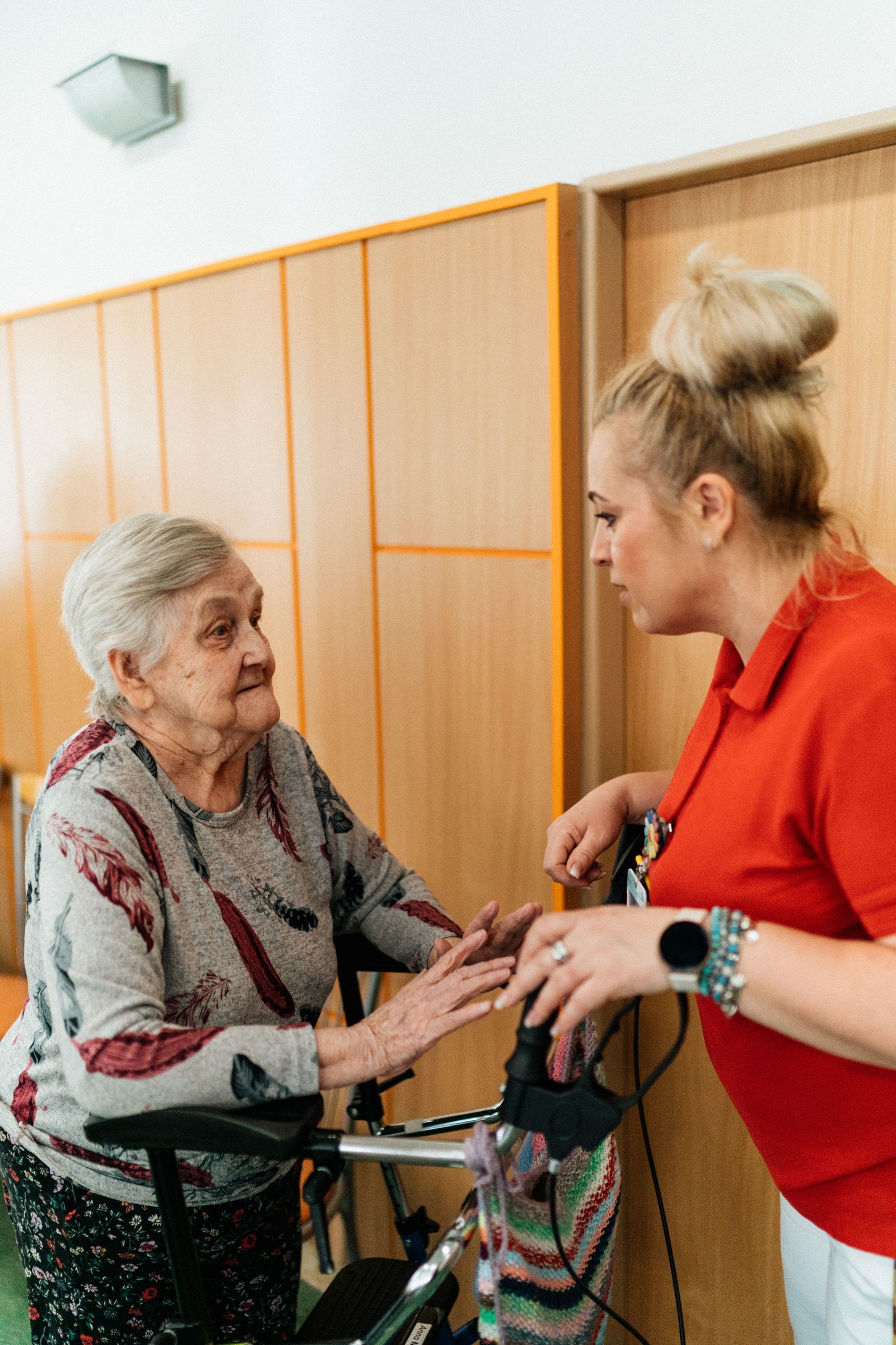 A carer talking with an older woman using a walking frame