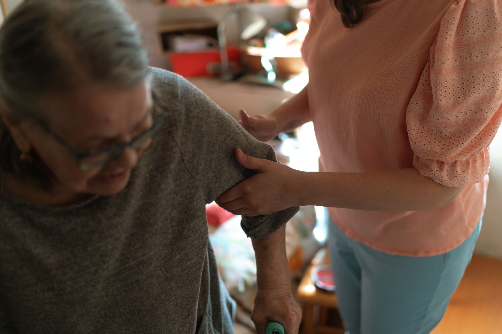 A caregiver offering an older woman support at home