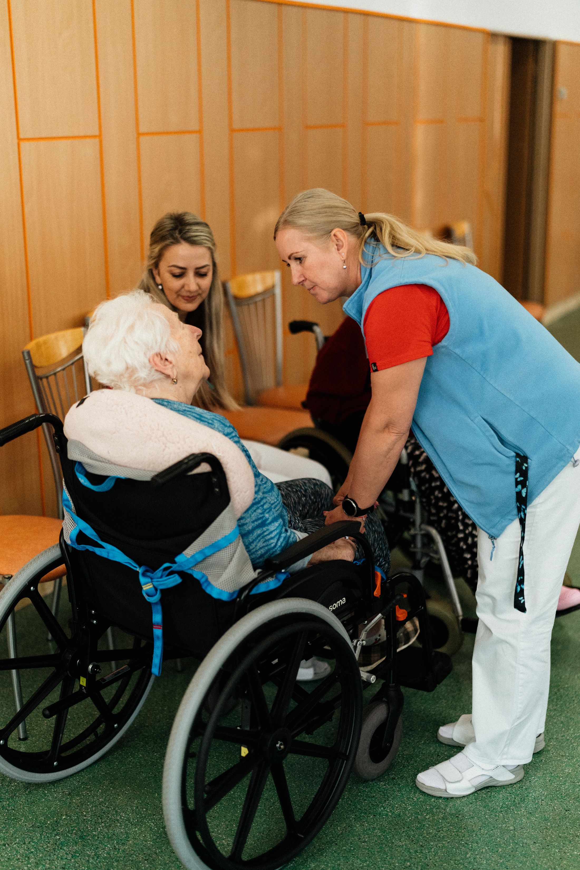 A caregiver talking with an older woman in a wheelchair